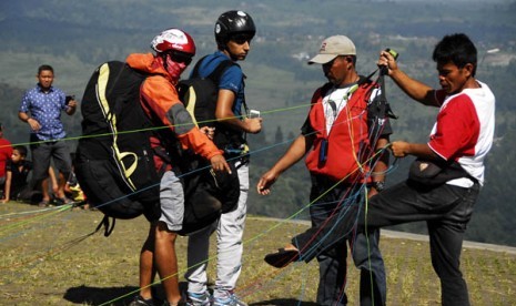 Wisatawan asal Timur Tengah (2 kiri) mendapat penjelasan sebelum melakukan penerbangan tandem bersama atlit paralayang di Puncak, Bogor, Jabar, Sabtu (2/8). 