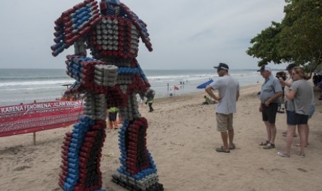 Wisatawan asing melihat boneka robot berbahan botol plastik bekas di Pantai Kuta, Rabu (27/12). 