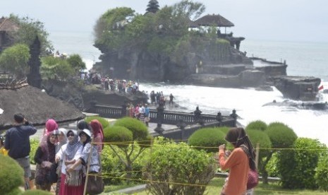 Wisatawan berfoto bersama dengan latar Pura Tanah Lot di Kabupaten Tabanan, Bali, Sabtu (26/12). 