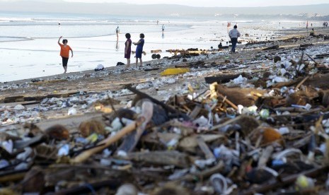 Wisatawan berfoto di antara tumpukan sampah yang terdampar di Pantai Kuta, Bali, Senin (15/2).