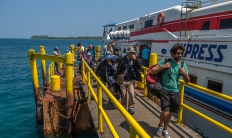 Wisatawan berjalan di dermaga pelabuhan kapal penumpang usai tiba di Karimunjawa, Jepara, Jawa Tengah, Selasa (24/7).