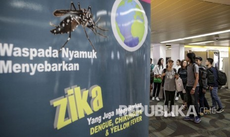  wisatawan berjalan melewati sebuah banner himbauan kewaspadaan terhadap virus Zika di Bandara Internasional Soekarno-Hatta di Tangerang.