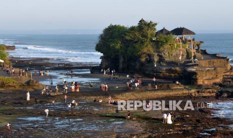 Wisatawan pada musim liburan menikmati suasana di Pantai Tanah Lot, Kabupaten Tabanan, Provinsi Bali, Ahad (16/5/2021).