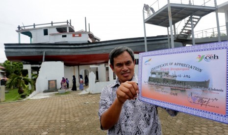 Wisatawan mancanegara asal Malaysia memperlihatkan sertifikat yang diperoleh seusai mengunjungi situs tsunami kapal di atas rumah pada hari peringatan 12 tahun bencana gempa dan tsunami di Banda Aceh, Aceh, Senin (26/12). 