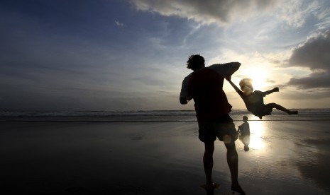 Wisatawan mancanegara bermain bersama anaknya di pantai Seminyak, Bali, Kamis (28/2).