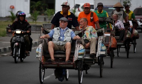 Wisatawan mancanegara (wisman) naik becak berkeliling kota saat melintas di Alun-Alun Selatan, Yogyakarta, Kamis (24/7). 