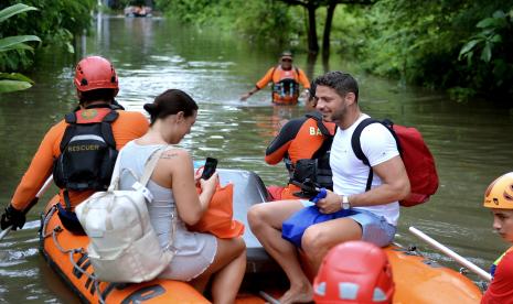 Wisatawan mancanegara (wisman) yang terjebak banjir berfoto saat dievakuasi tim SAR menggunakan perahu karet di kawasan Seminyak, Badung, Bali, Sabtu (8/10/2022). Tim SAR gabungan mengevakuasi puluhan wisman dari sejumlah vila yang terendam banjir dengan ketinggian sekitar 1,5 meter di kawasan pariwisata itu akibat hujan yang mengguyur Bali sejak Jumat (7/10). 