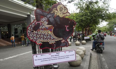 Wisatawan melintas di dekat wayang berukuran besar yang dipasang di jalur pedestrian Malioboro, Yogyakarta. Pemkot Yogyakarta mengantisipasi adanya kenaikan wisatawan saat libur akhir tahun.