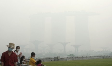  Wisatawan memakai masker saat berwisata melihat Marina Bay Sands Casino dan Supertree grove yang terselubung kabut asap di Singapura, Kamis (20/6).   (AP/Joseph Nair)