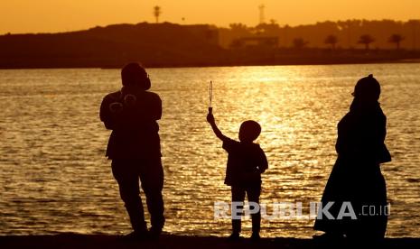  Arab Saudi akan Buka Kembali Sekolah pada 30 Agustus. Wisatawan memakai masker untuk membantu mencegah penyebaran virus corona, ketika seorang bocah meniupkan gelembung saat matahari terbenam di pantai Laut Merah, di Jeddah, Arab Saudi.