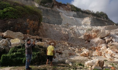 Wisatawan memotret reruntuhan tebing akibat gempa bumi di kawasan obyek wisata Pantai Melasti, Badung, Bali, Selasa (16/7/2019).