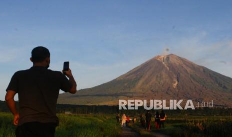 Wisatawan memotret saat awan panas belum keluar dari kawah gunung Semeru di desa Supiturang, Pronojiwo, Lumajang, Jawa Timur, Jumat (10/12/2021). 