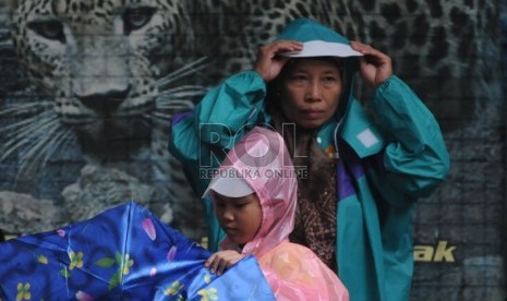   Wisatawan mengenakan jas hujan saat hujan turun di Kebun Binatang Ragunan,Jakarta,Selasa (25/12). (Republika/Aditya Pradana Putra)