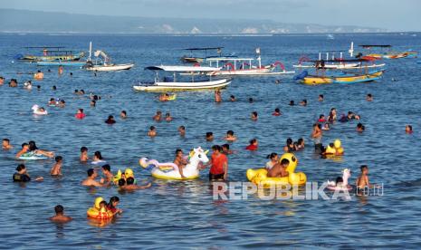 Wisatawan menikmati liburan di pantai, (ilustrasi). Satgas meminta masyarakat untuk belajar dari kenaikan kasus Covid-19 setiap momen liburan panjang.