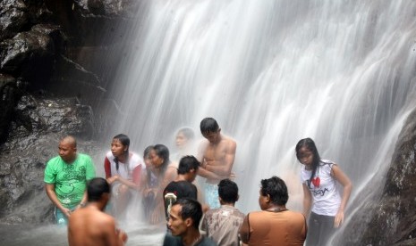 Wisatawan menikmati mandi di bawah guyuran air terjun. (ilustrasi) 