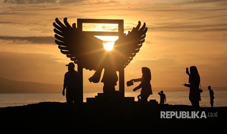 Wisatawan menikmati suasana matahari terbit pertama kali tahun 2018 di Pantai Boom, Banyuwangi, Jawa Timur, Senin (1/1). 