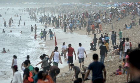 Wisatawan menikmati suasana Pantai Kuta, Badung, Bali, Minggu (31/12). Pantai Kuta dipadati oleh ribuan wisatawan domestik maupun mancanegara jelang perayaan malam pergantian tahun baru 2018.