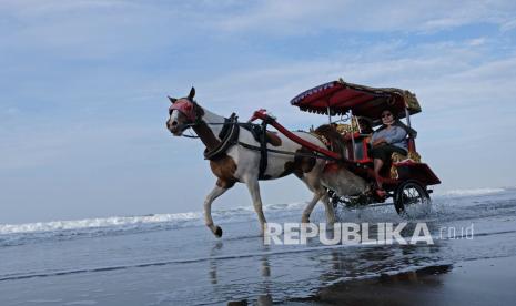 Wisatawan naik andong wisata menyusuri Pantai Parangtritis, Kretek, Bantul, DI Yogyakarta, Sabtu (6/11/2021). Sejak dibuka kembali untuk umum, sejumlah lokasi wisata di Kabupaten Bantul mulai ramai dikunjungi wisatawan terutama pada hari Sabtu dan Minggu yang disambut gembira oleh pelaku wisata.