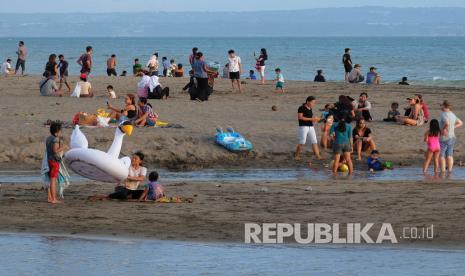 Wisatawan tanpa menggunakan masker berkunjung di Pantai Berawa, Badung, Bali, Jumat (19/6/2020). Pemerintah Provinsi Bali berencana menerapkan tiga tahapan implementasi protokol kesehatan menyambut normal baru mulai 9 Juli 2020, di mana sektor pariwisata baru akan dibuka pada tahapan terakhir.