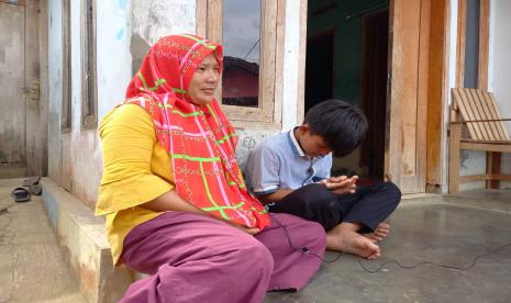 Wiwin (30 tahun), bersama anaknya, Irsyad (13), di rumahnya, Kampung Hergamanah, Desa Ciawang, Kecamatan Leuwisari, Kabupaten Tasikmalaya, Senin (9/1/2023). Irsyad merupakan salah satu korban keracunan ciki ngebul di Kabupaten Tasikmalaya beberapa waktu lalu. Gubernur Jabar Ridwan Kamil akan menggelar rapat khusus untuk membahas chiki ngebul.