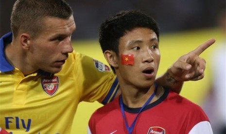 Xuan Tien (kanan) bersama striker Arsenal, Lukas Podolski, dalam sebuah pertandingan. 