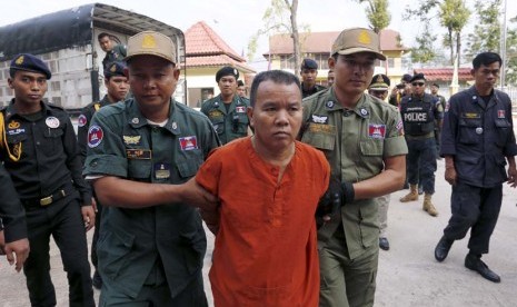 Yem Chrin (tengah) digiring aparat kepolisian saat tiba di pengadilan Battambang, Kamboja, Kamis (3/12). 