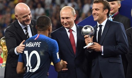 Kylian Mbappe berjabat tangan dengan Presiden Rusia Vladimir Putin (kedua dari kanan) sebelum menerima penghargaan sebagai pemain muda terbaik pada Piala Dunia 2018 dari Presiden Prancis Emmanuel Macron (kanan). 