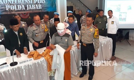 YR (56 tahun) marbut Masjid Agung Pameungpeuk, Kabupaten Garut, tengah memperagakan cara dia mengikat kaki, wajah dan tangan di hadapan para wartawan di Mapolda Jabar.