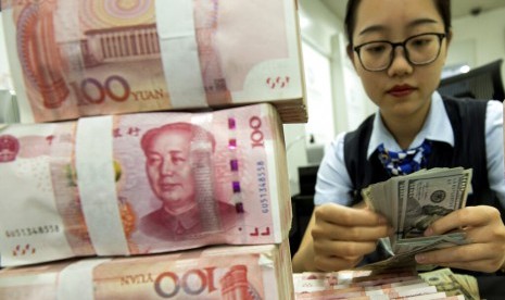 YUAN. Petugas bank menghitung dolar AS di samping tumpukan yuan Cina di Hai'an, Provinsi Jiangsu, China, Selasa (6/8). Nilai tukar yuan Cina merosot tajam atas dolar AS sebagai akibat dari perang dagang dengan Amerika Serikat.