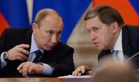 Yuri Ushakov (kanan) berbincang dengan Presiden Vladimir Putin