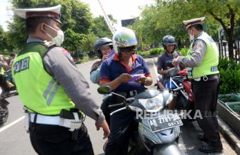 Aparat kepolisian Polresta Yogyakarta mengecek masker pengendara bermotor di perempatan titik nol Yogyakarta, Kamis (23/4). Selain memeriksa dan menghimbau pengendara menggunakan masker, aparat juga membagikan masker bagi pengendara yang tidak memakai