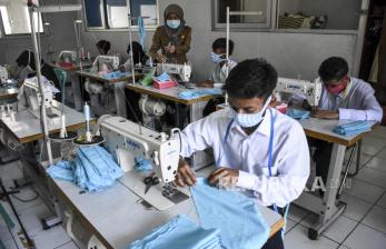 Guru membimbing siswa penyandang disabilitas menyelesaikan produksi masker berbahan kain di Dinas Sosial Provinsi Jawa Barat, Kota Cimahi, Senin (6/4). Masker berbahan kain buatan siswa penyandang disabilitas tersebut untuk dibagikan gratis kepada tenaga medis di puskmesmas, pengemudi ojek daring, petugas kebersihan, pedagang dan masyarakat umum yang memerlukan sebagai bentuk kepedulian dalam upaya mencegah penyebaran virus Corona (Covid-19) 