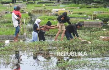 In Picture: Banjir Tak Surutkan Niat Warga untuk Ziarah Kubur Jelang Ramadhan