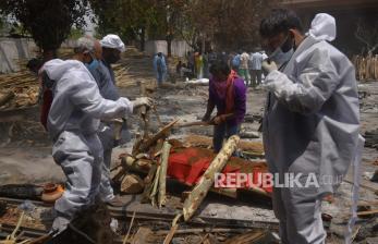 Anggota keluarga, yang mengenakan Alat Pelindung Diri (APD), melakukan upacara terakhir untuk korban COVID-19 selama pemakaman mereka di tempat kremasi di New Delhi, India, Kamis (29/4).