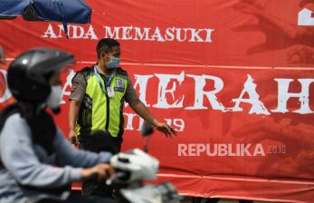 Seorang petugas keamanan berjaga dengan latar belakang spanduk pemberitahuan lokasi zona merah Covid-19 (ilustrasi)