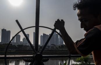 Seorang warga memutar pintu air dengan latar belakang deretan gedung bertingkat di Jakarta, Kamis (25/8/2022). Pemerintah menetapkan target defisit Anggaran Pendapatan dan Belanja Negara (APBN) 2023 mencapai Rp598,2 triliun atau setara 2,85 persen terhadap Produk Domestik Bruto (PDB).