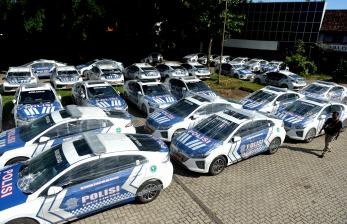 Warga berjalan di dekat mobil listrik yang akan digunakan personel Polri saat Konferensi Tingkat Tinggi (KTT) G20 di kawasan Nusa Dua, Badung, Bali, Sabtu (29/10/2022). Ratusan unit kendaraan listrik yang akan digunakan polisi untuk pengamanan dan pengawalan selama KTT G20 itu mulai tiba di Bali. 