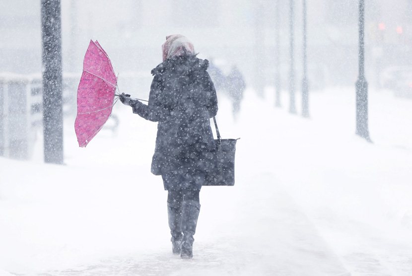  Payung milik seorang pejalan kaki tertiup angin kencang saat badai salju terjadi di Philadelphia, Selasa (21/1) waktu setempat.    (AP/Matt Rourke)