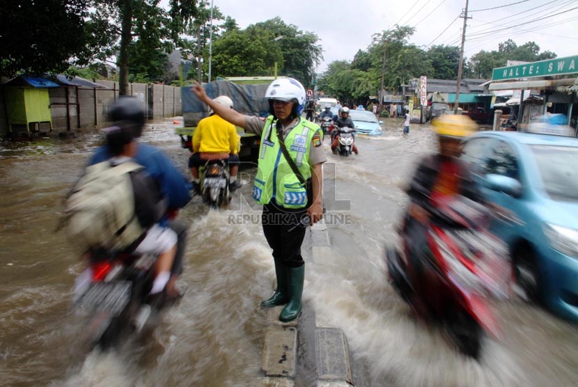   Polisi mengatur lalu lintas saat banjir menggenangi ruas jalan yang menghubungkan Ciledug dengan Cipulir, Jakarta Selatan (29/1).   (Republika/Yasin Habibi)