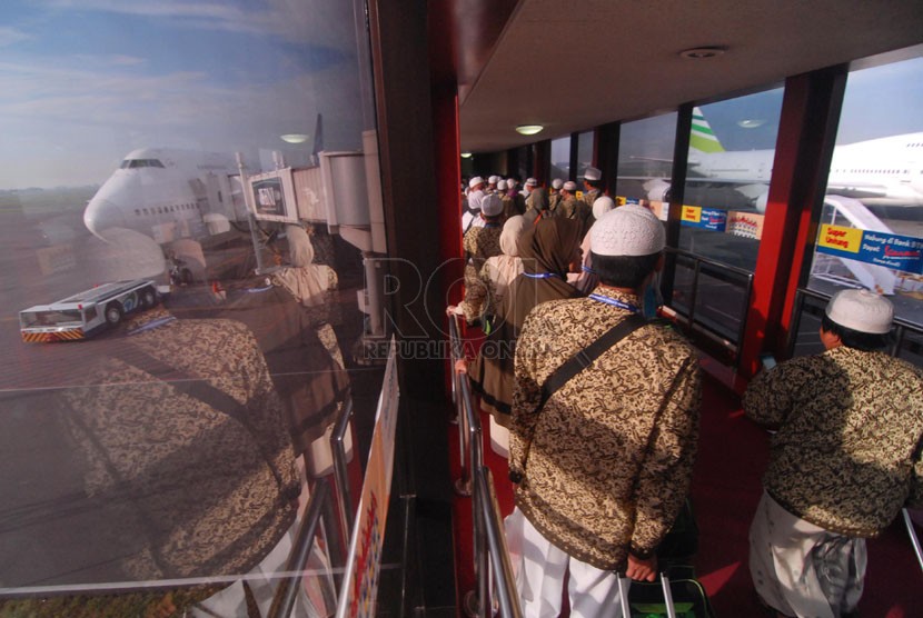   Para calon jamaah umrah menuju kabin pesawat Garuda Indonesia usai peresmian rute penerbangan langsung Surabaya-Jeddah di bandara Juanda, Surabaya, Ahad (13/4). (Republika/Rakhmawaty La