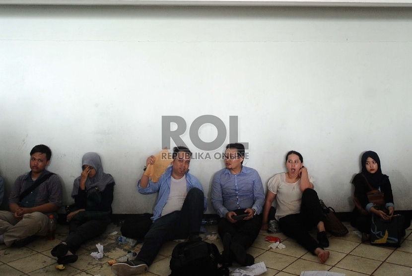 Pencari kerja istirahat saat mengantre untuk dapat masuk kedalam lokasi bursa kerja di Komplek Gelora Bung Karno, Jakarta, Selasa (11/8).   (Republika/Tahta Aidilla)