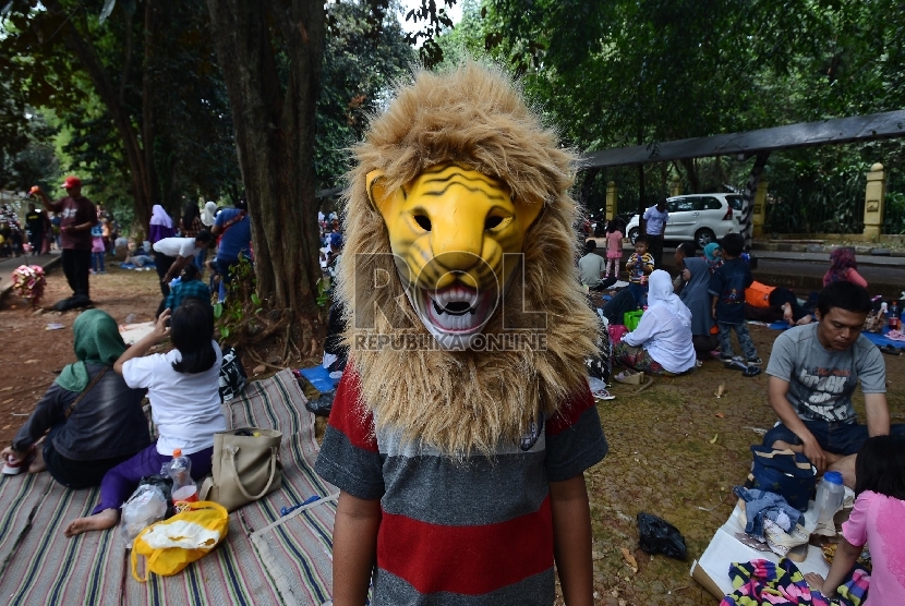 Seorang anak dengan memakai topeng harimau bermain di Taman Margasatwa Ragunan, Jakarta Selatan, Sabtu (18/7).   (Republika/Raisan Al Farisi)