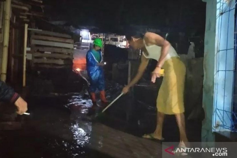 Warga membersihkan tumpukan lumpur yang terbawa air bah. Banjir setinggi pinggang orang dewasa melanda Kampung Baru, Kelurahan Sayang, Kabupaten Cianjur, Ahad (27/10).