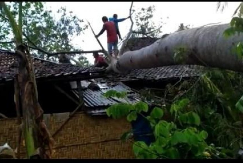  Warga berusaha memotong batang pohon yang menimpa rumah di Kecamatan Jatisrono, Wonogiri. Dok. Kodim 0728