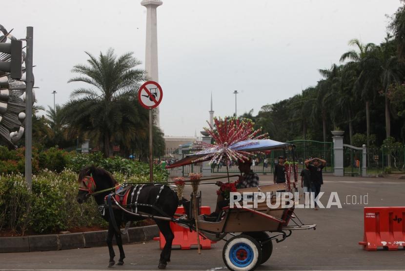 Delman menunggu penumpang di Kawasan Monumen Nasional (Monas), Jakarta, Ahad (7/1).