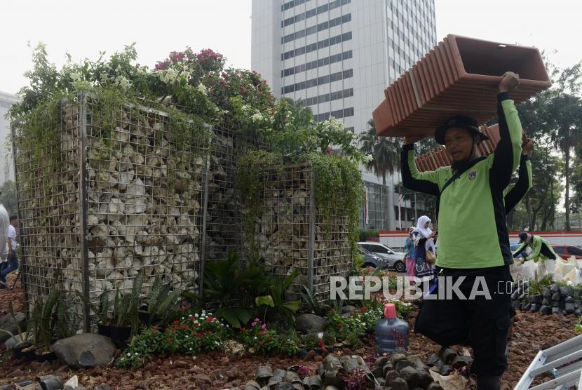 Petugas membawa pot di dekat instalasi batu gabion di Bundaran HI, Jakarta, Jumat (23/8).