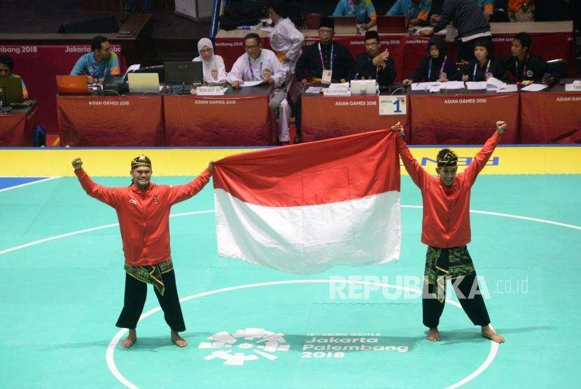 Pesilat Indoensia Yola Primadona Jampil dan Hendy membawa bendera merah putih usai final cabang pencak silat kelas artistik ganda putra Asian Games 2018 di Padepokan Pencak Silat TMII, Jakarta, Senin (27/8).