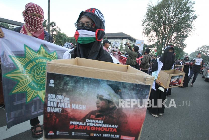 Ratusan massa dari sejumlah elemen organisasi menggelar aksi Save Ghouta, di depan Gedung Sate, Bandung, Jumat (2/3).