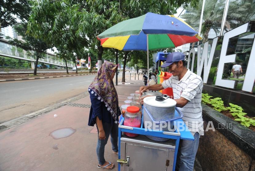 Pedagang berjualan di trotoar di kawasan Jalan Jendral Sudirman, Jakarta Pusat, Ahad (17/12).