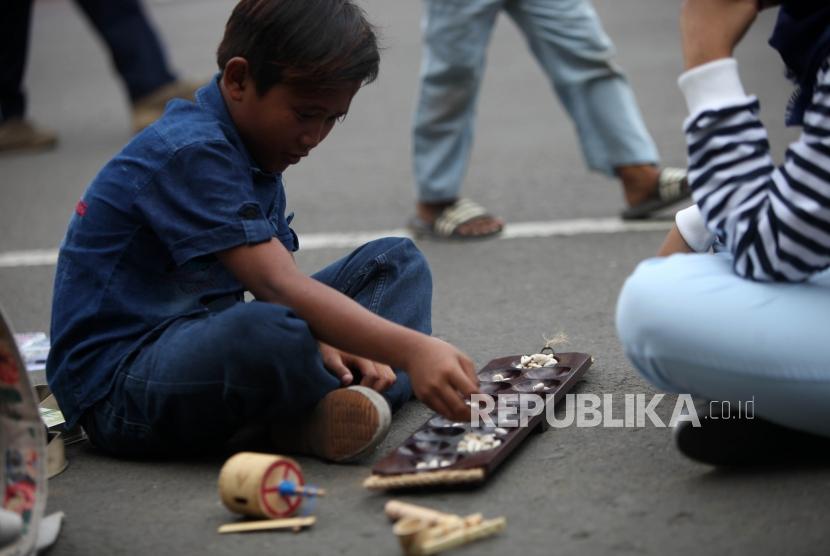 Seorang anak bermain congkak.